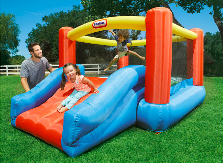 A father and two young children playing on a toddler bounce house
