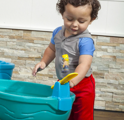 A Little Boy Playing With A Toy Attached To His Water Table.