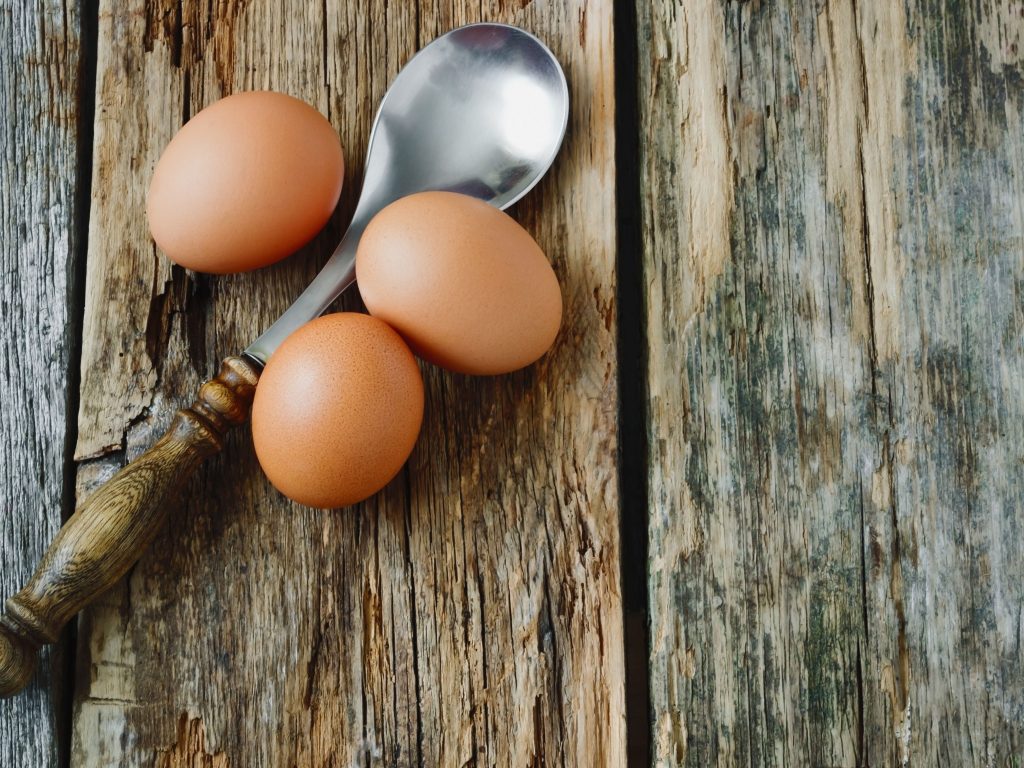 Three eggs and a spoon on a table. These are all the things you need to play the Egg and Spoon game with your kids.