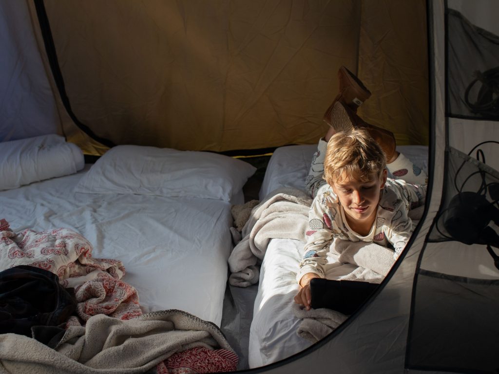 A Boy In A Tent While Camping In His Backyard.