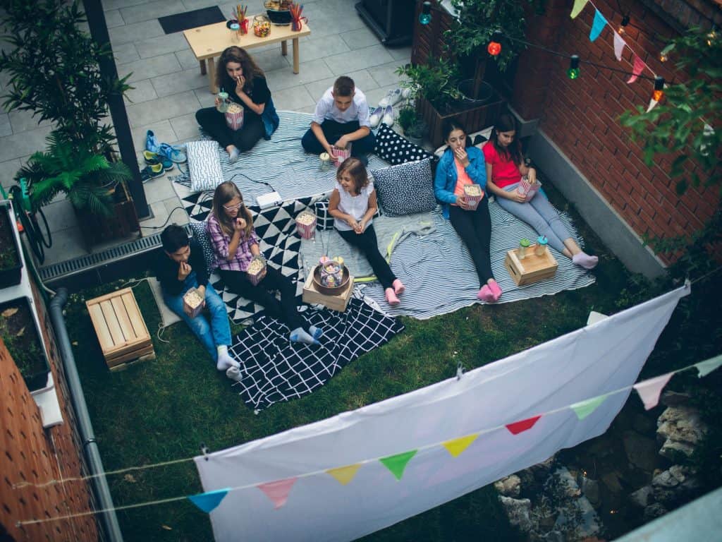 An Overhead View of Children Watching A Movie In A Backyard.