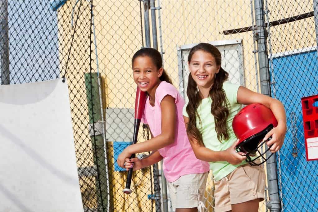 Two Girls Practicing In A Batting Cage.
