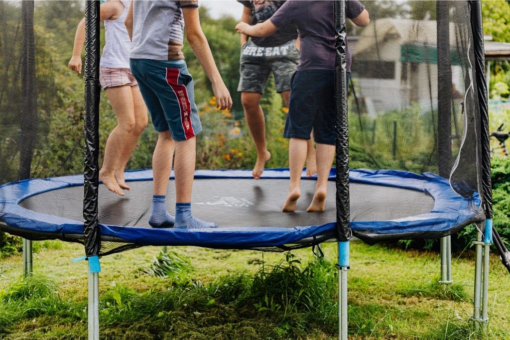 Kids Jumping On A Trampoline On A Sunny Day.